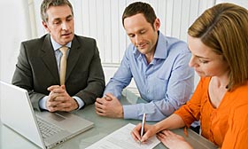 Couple signing mortgage papers. (© Image Source/DIRK LINDNER/Getty Images)